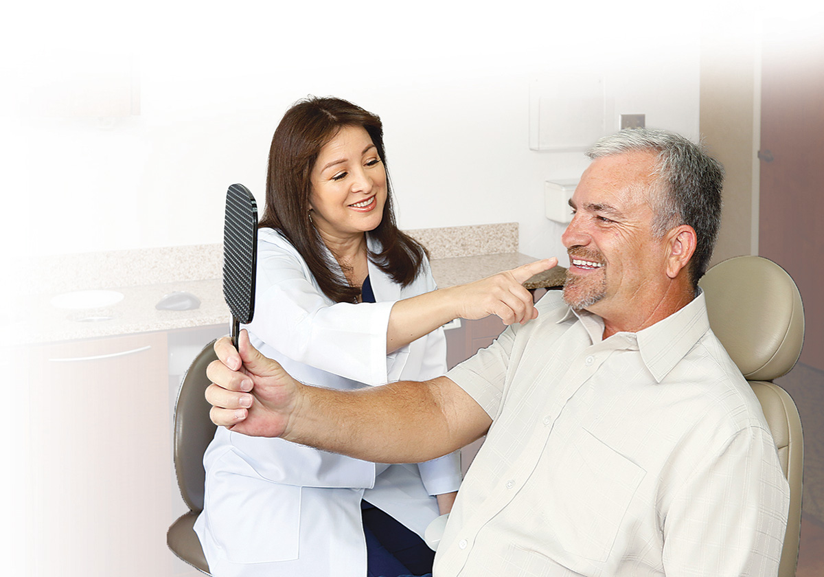 A patient examines his smile while Dr. Sanger looks on